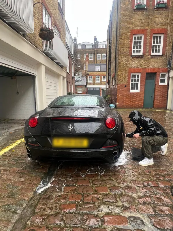 Ferrari California having its wheels cleaned in a London mews