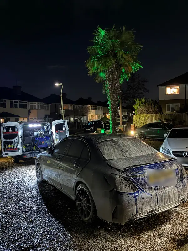 Mercedes-AMG in snow foam at night with the OMVA van open and lit behind it