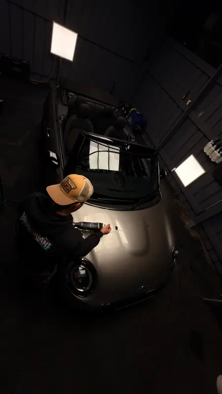 Omar machine-polishing the bonnet of a Mini under studio lights