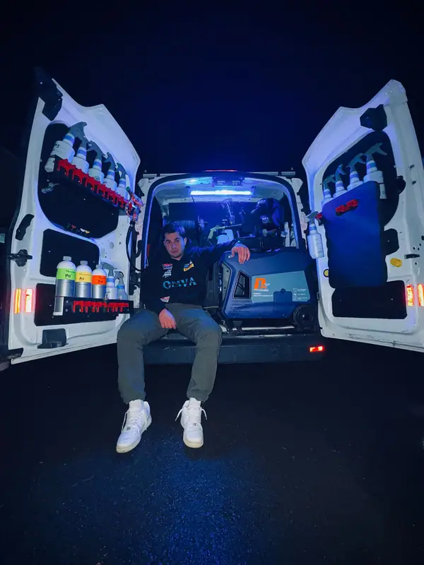 Omar sitting in the back of the OMVA van beside the generator, with Koch Chemie products on the doors
