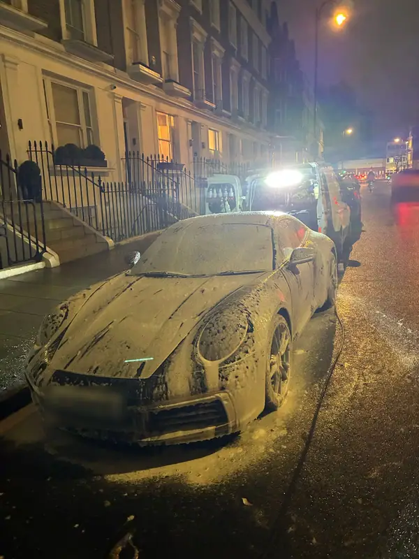 Porsche 911 covered in snow foam on a Chelsea street at night