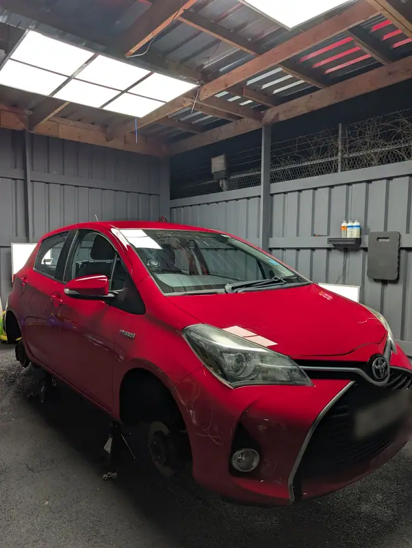 Red Toyota Yaris on axle stands with its wheels off in the OMVA studio